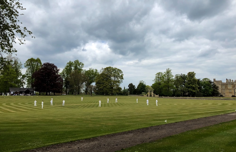 men on grassy plain field under heavy clouds