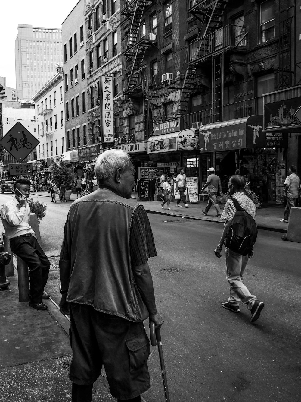 Graustufenfotografie von Menschen, die in der Nähe der Straße spazieren gehen