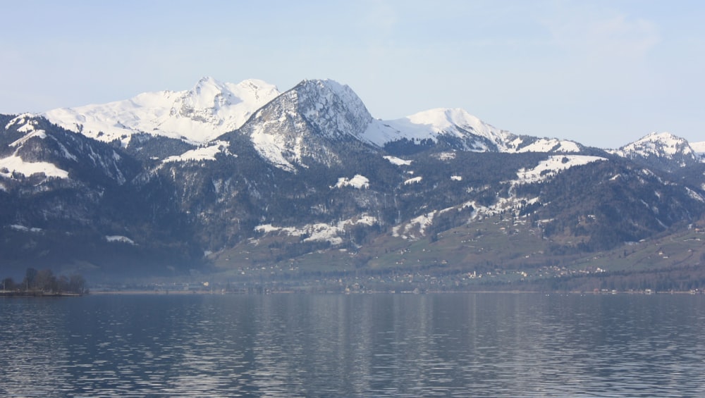 body of water near snow capped mountain during daytime