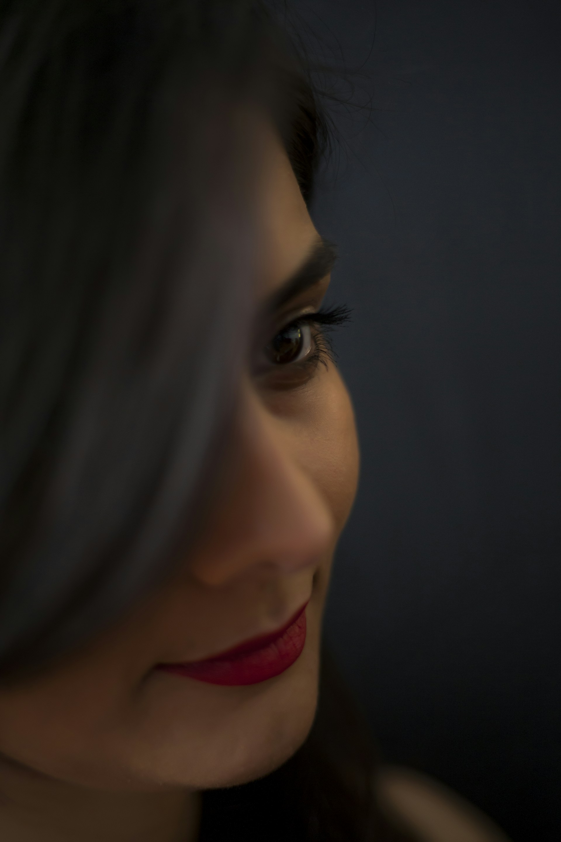 Close-up of a mysterious, teasing glance from a woman with bold makeup under neon lighting, capturing a modern, seductive vibe.