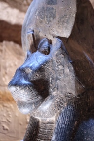 Close-up of an old statue representing a Mesopotamian deity surrounded by ancient artifacts.