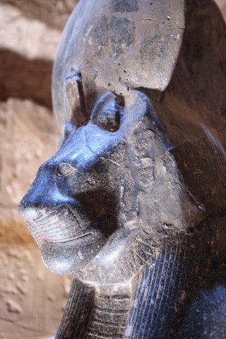 Close-up of an old statue representing a Mesopotamian deity surrounded by ancient artifacts.