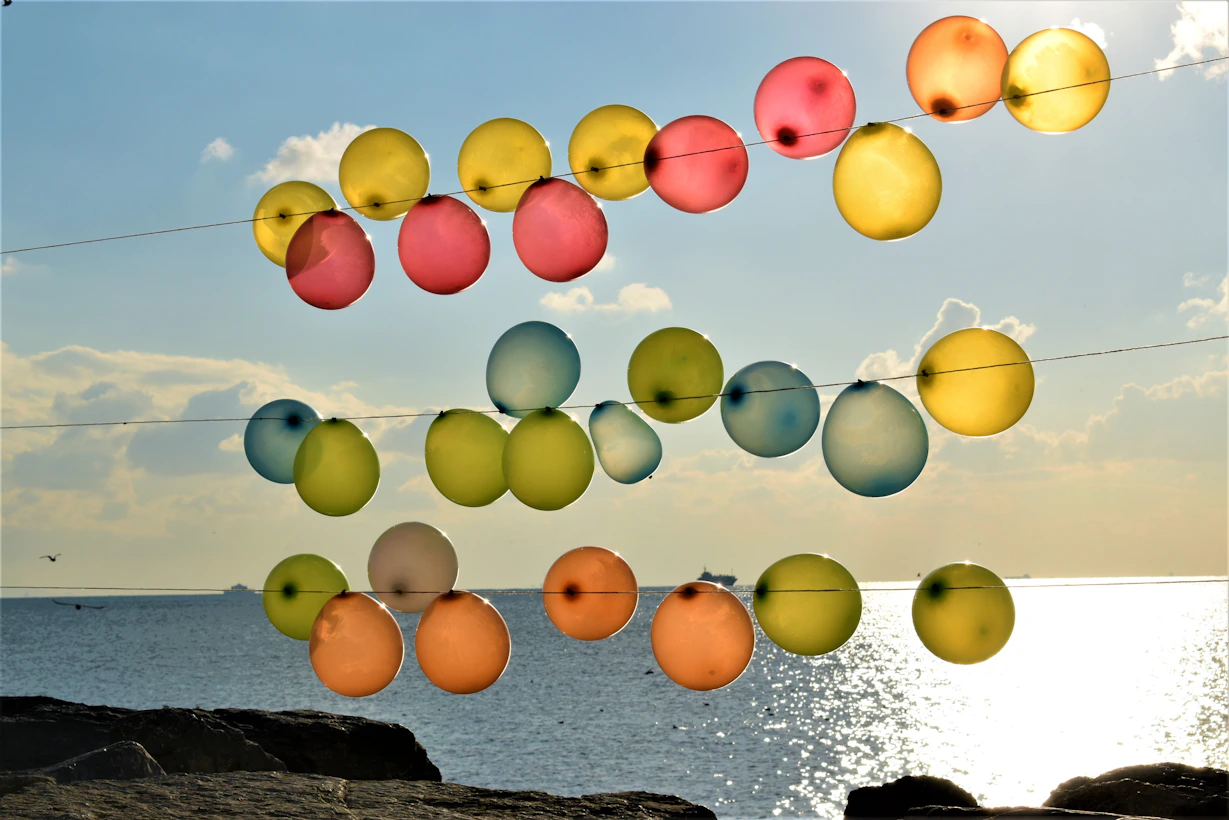 Sunlight filtering through soft colors of balloons during an outdoor celebration.