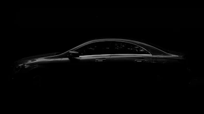 Side view of a sleek white sedan with a spotless shine on a dark background.