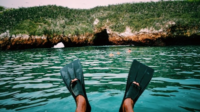 A pair of black diving fins partially submerged in shallow turquoise water