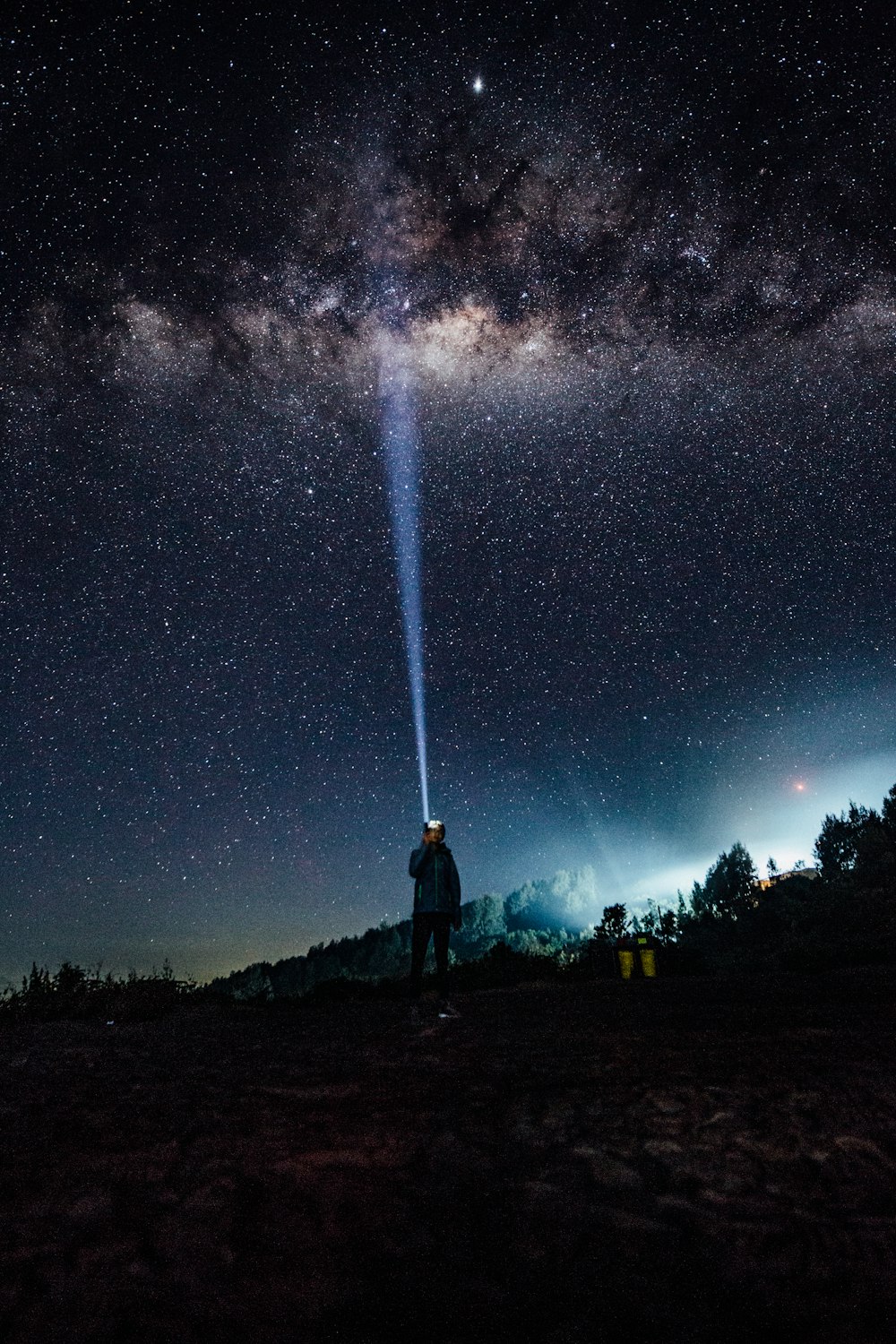 a man standing on a hill under a night sky filled with stars