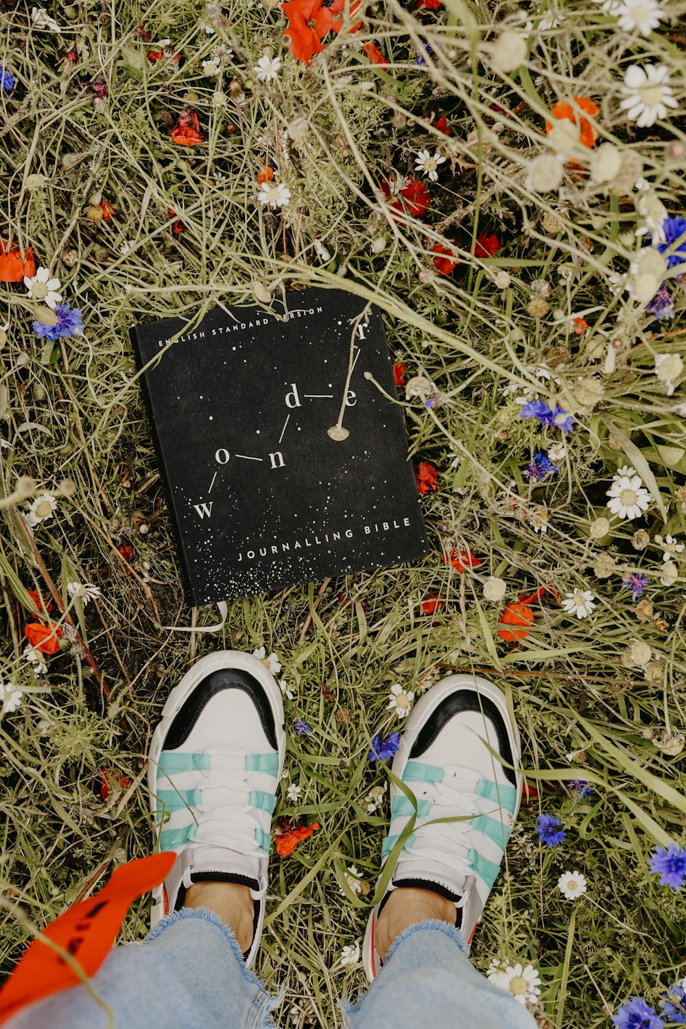 black and white hardbound book on field surrounded with assorted-color flowers