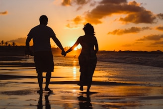 couple standing on body of water during golden hour