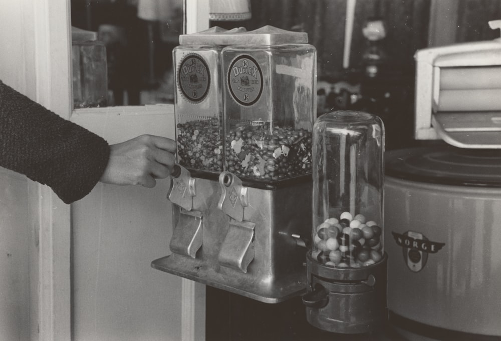 person's hand on gumball dispenser