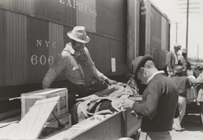 Team members collaborating on rail logistics planning beside a row of railcars.