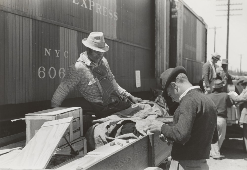 grayscale photography of two men beside train