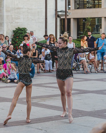 Invited salsa performers showing their skills on an open-air stage with city buildings behind.