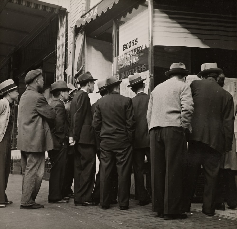 grayscale photography of men standing near house