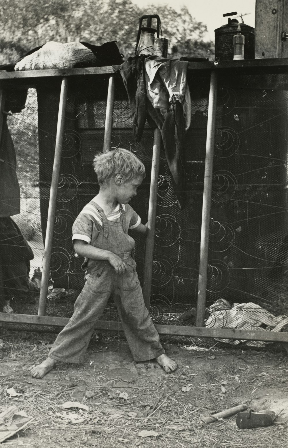 boy standing near grilles in grayscale