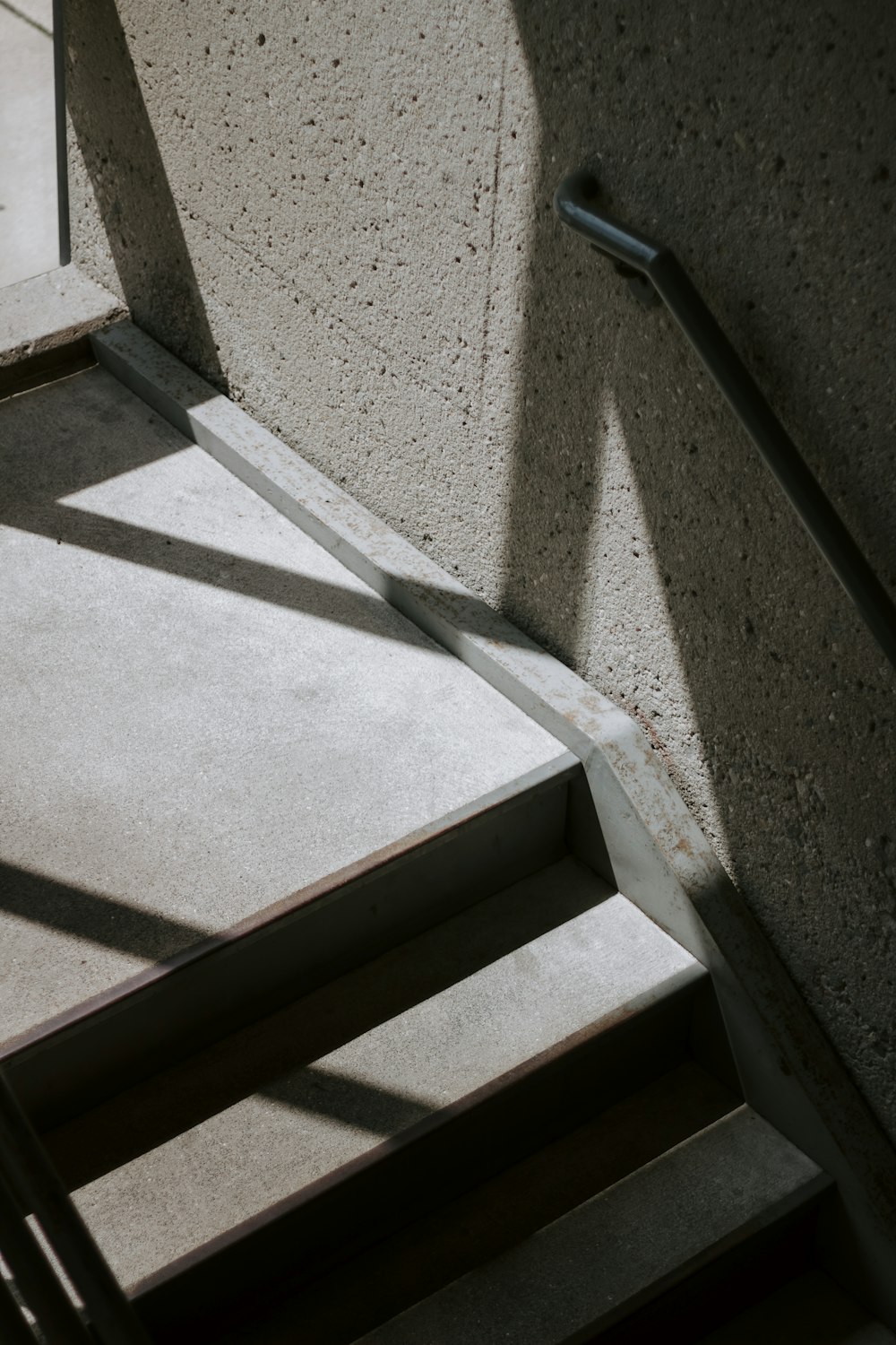a stair case with a hand rail and a concrete wall