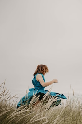 A child twirling in a bright, patterned dress under a clear blue sky.