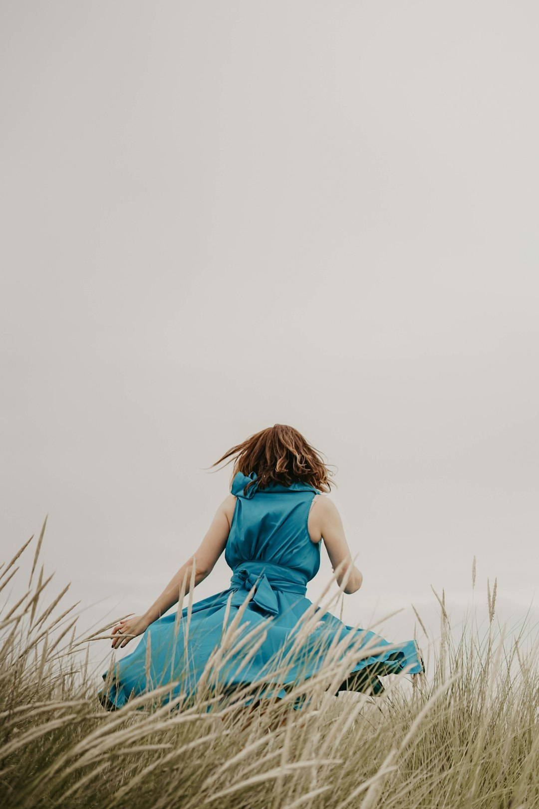 woman wearing blue dress standing on grass field