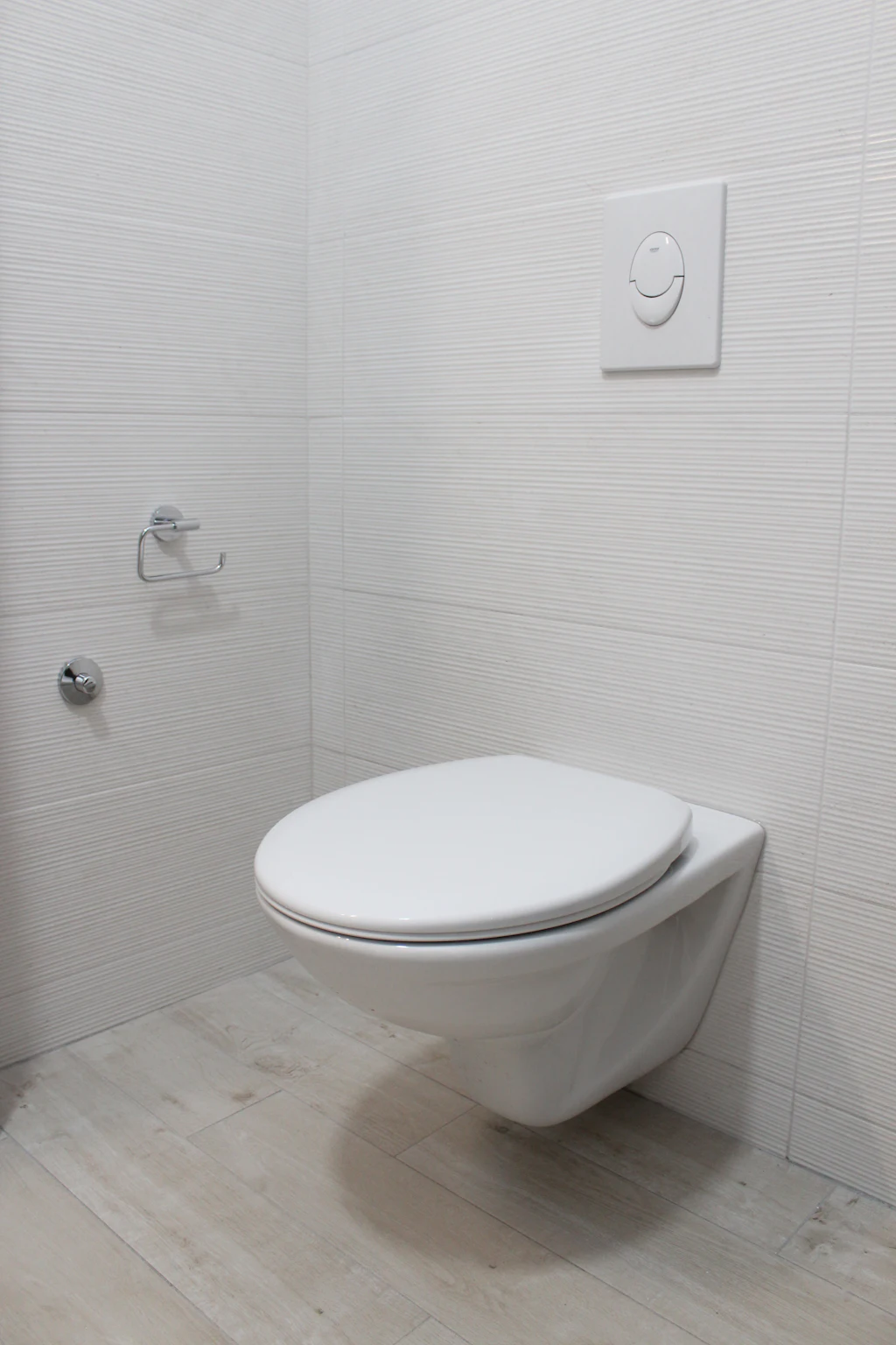 Um vaso sanitário branco com a tampa fechada em um banheiro revestido de azulejos