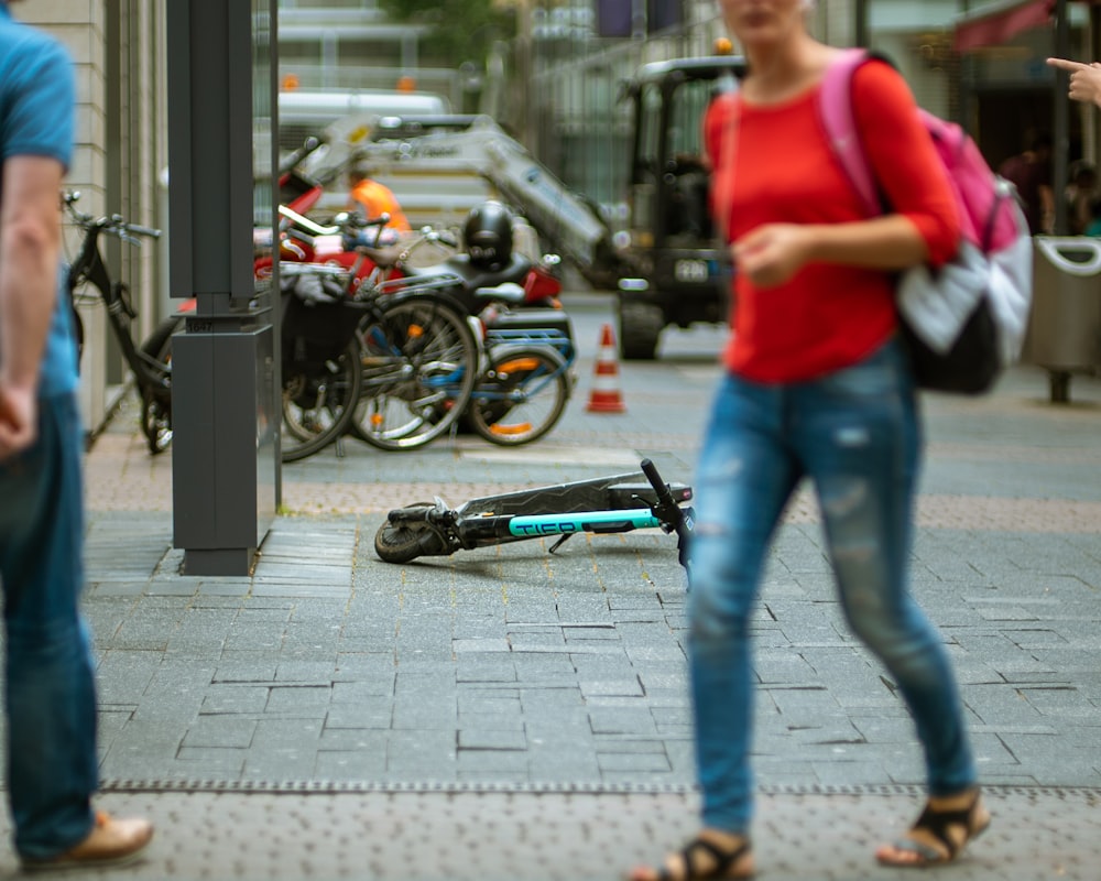 femme marchant sur le sentier à côté d’un scooter sur la route