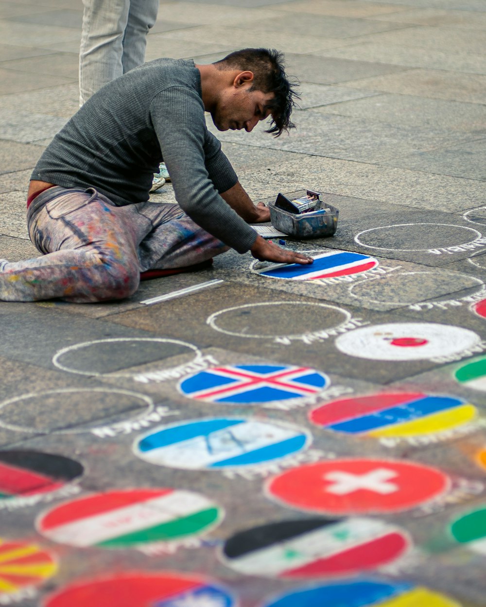 man painting assorted flags on concrete pavement during daytime
