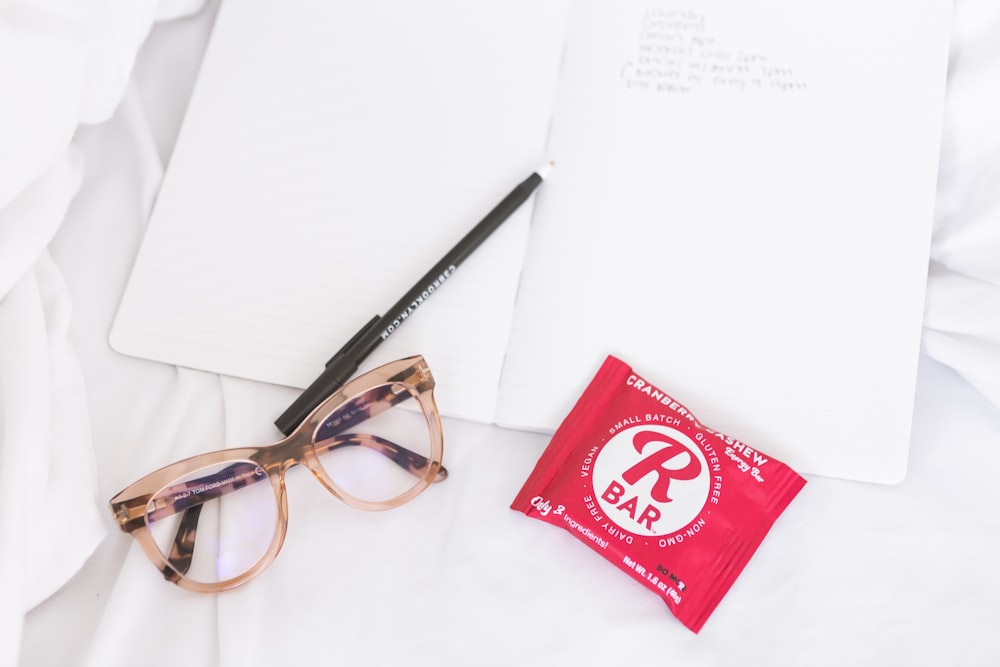 a pair of glasses sitting on top of a bed next to a notepad