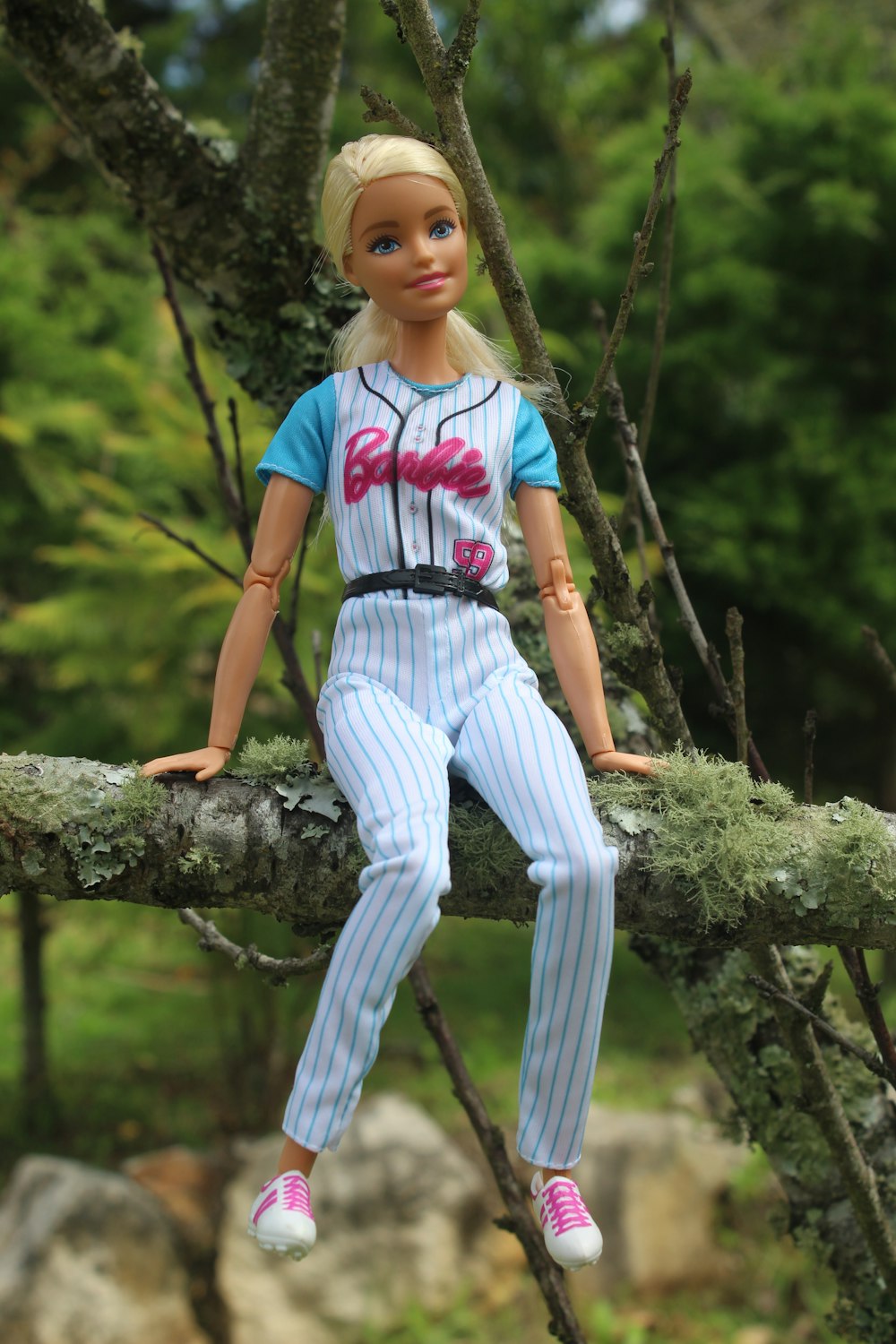 muñeca con camiseta de béisbol sentada en la rama del árbol durante el día