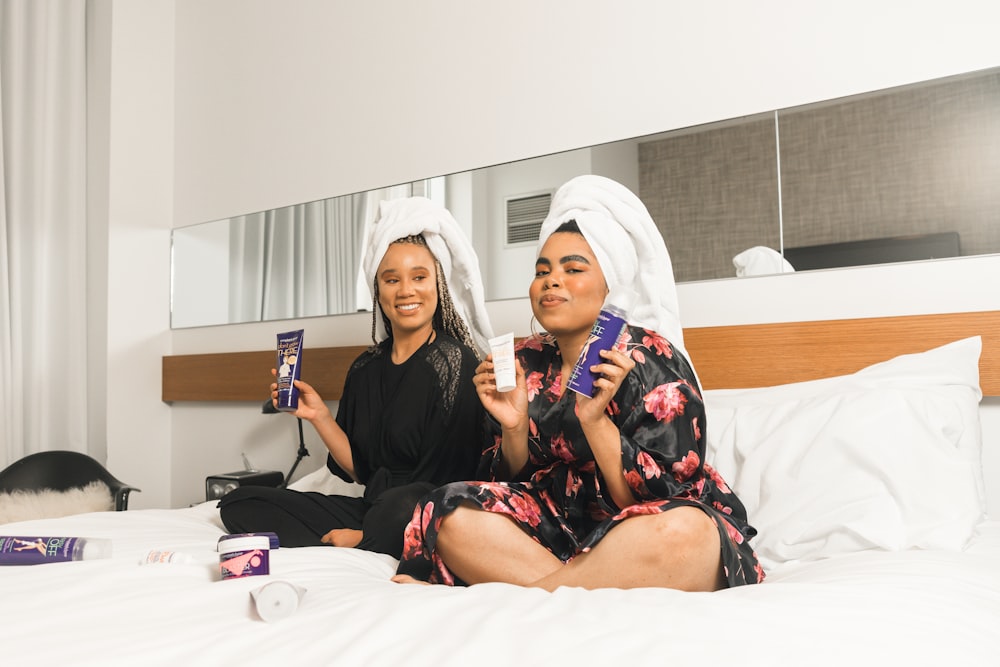 two women in bathrobe sitting on bed