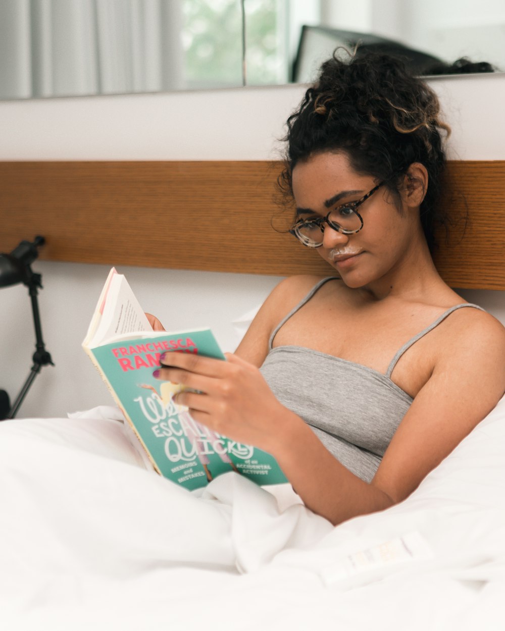 woman in gray spaghetti strap reading book