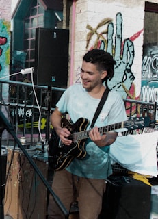 A street musician playing reggae guitar with a joyful expression in a lively neighborhood.