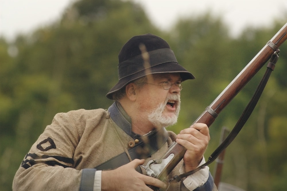 person carrying brown rifle