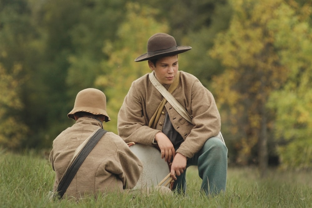 two men sitting on green field