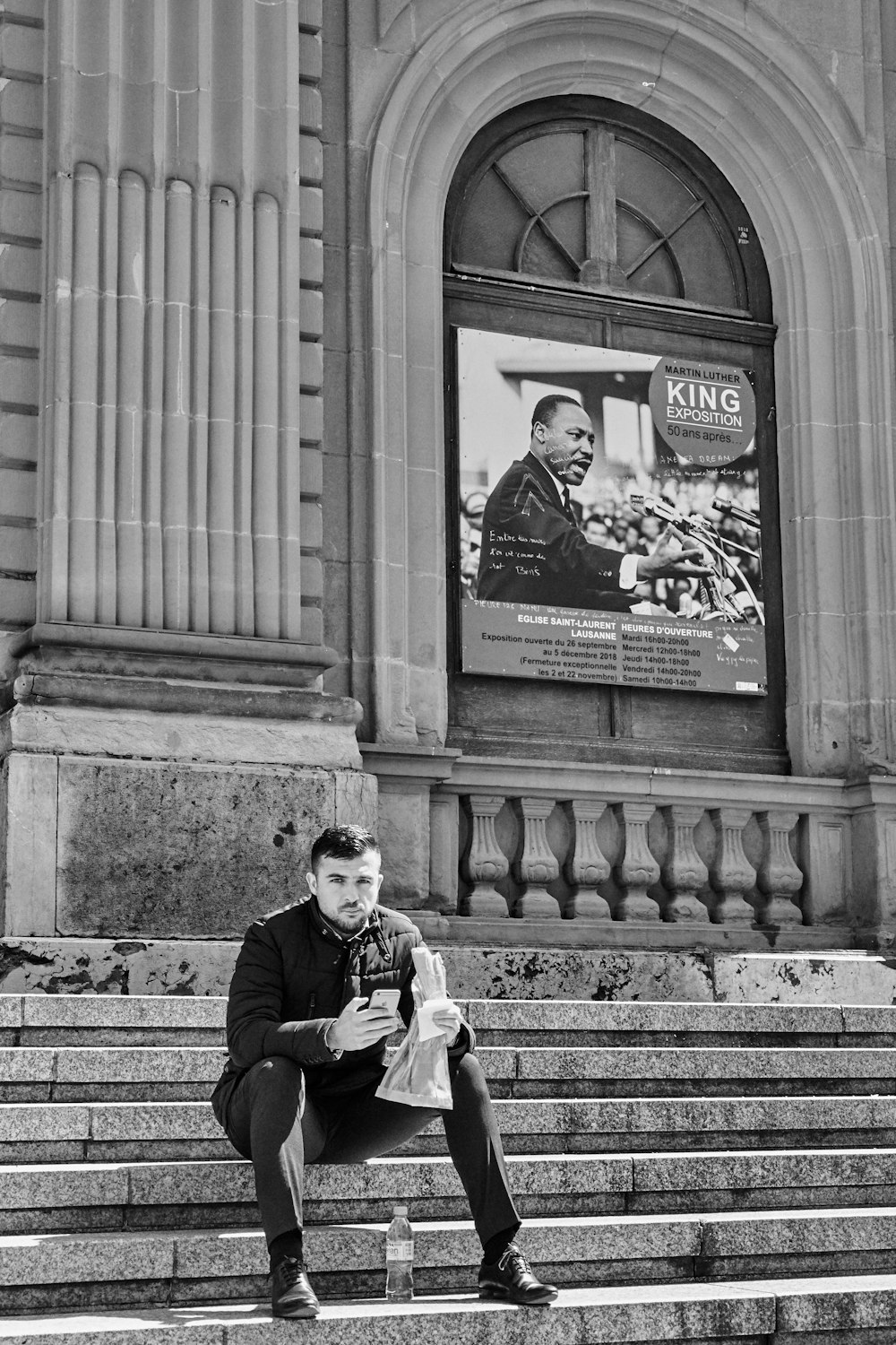 grayscale photography of man sitting on a stairs