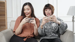 Happy users engaging with a mobile game on their phones in a cozy living room setting.