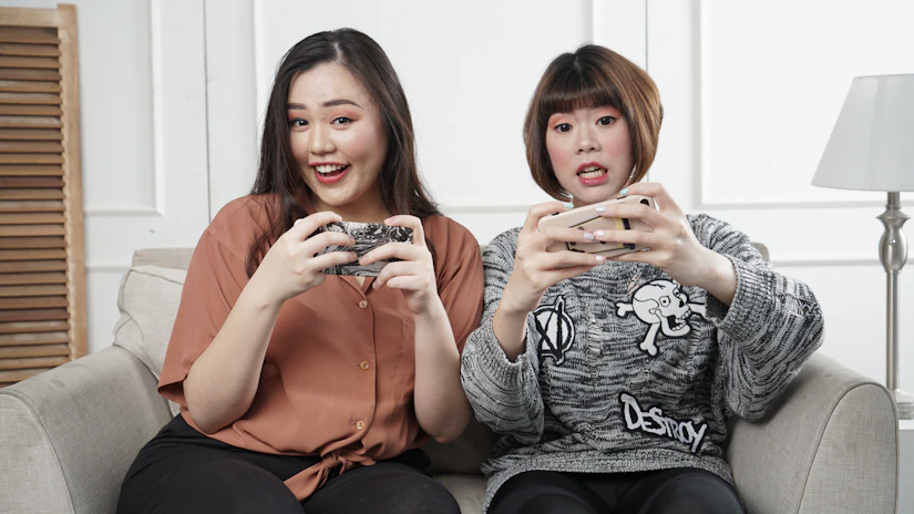 A diverse group of people happily playing mobile games together in a cozy living room.