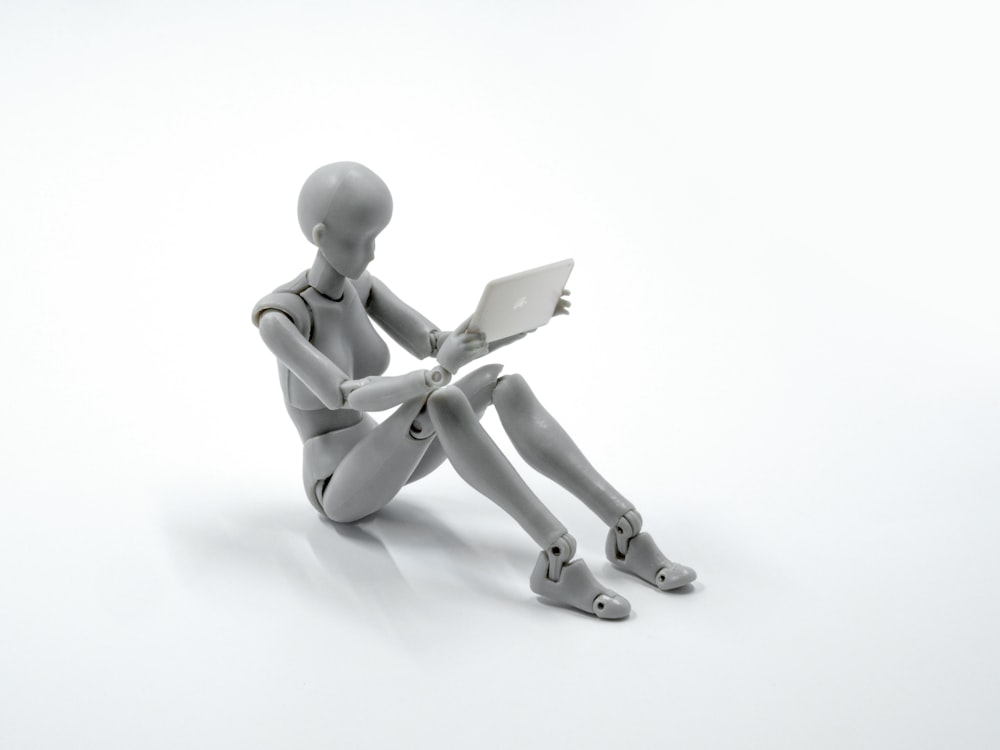 manikin figurine holding an iPad miniature