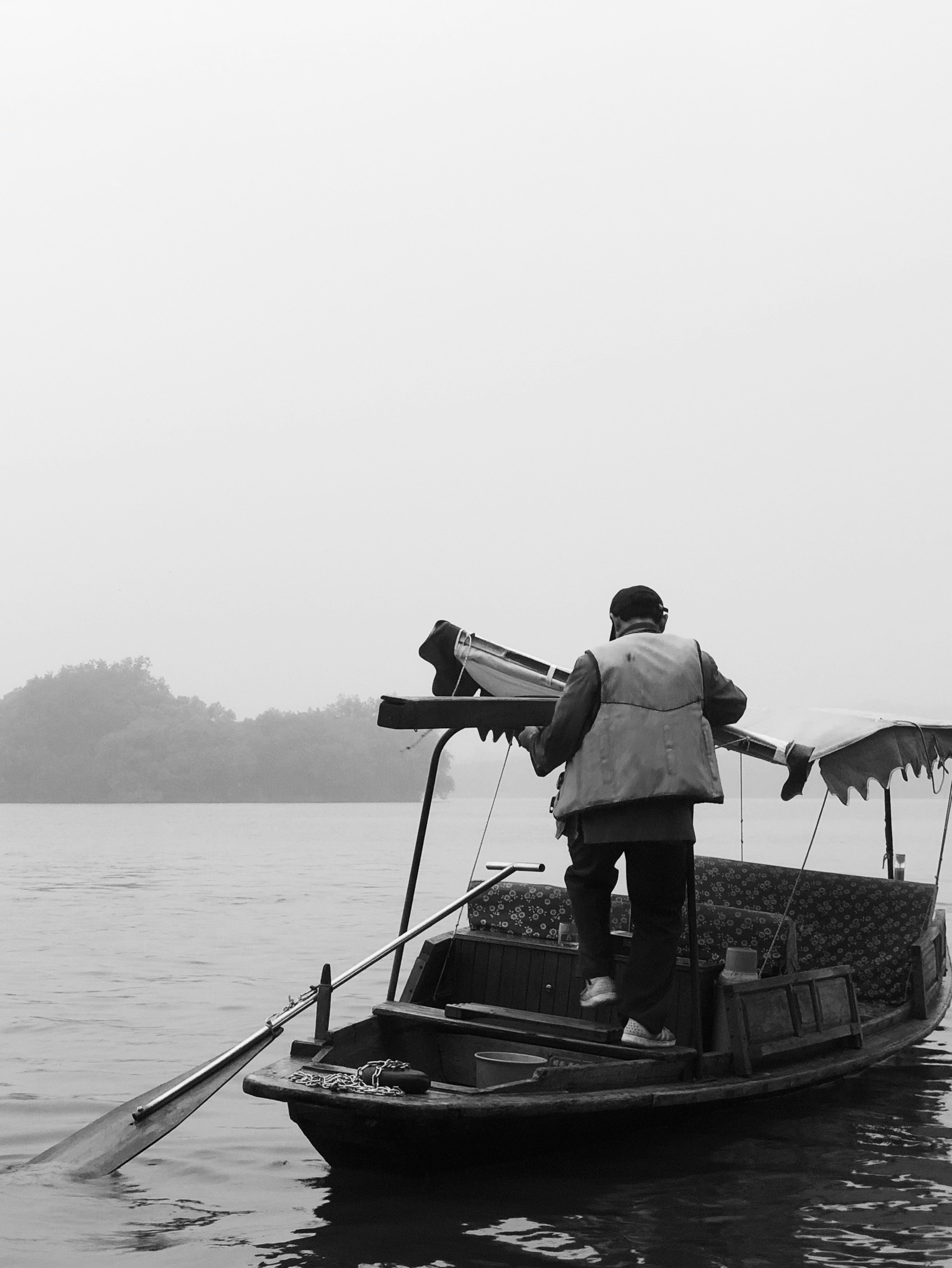 grayscale photography of person standing on floating boat