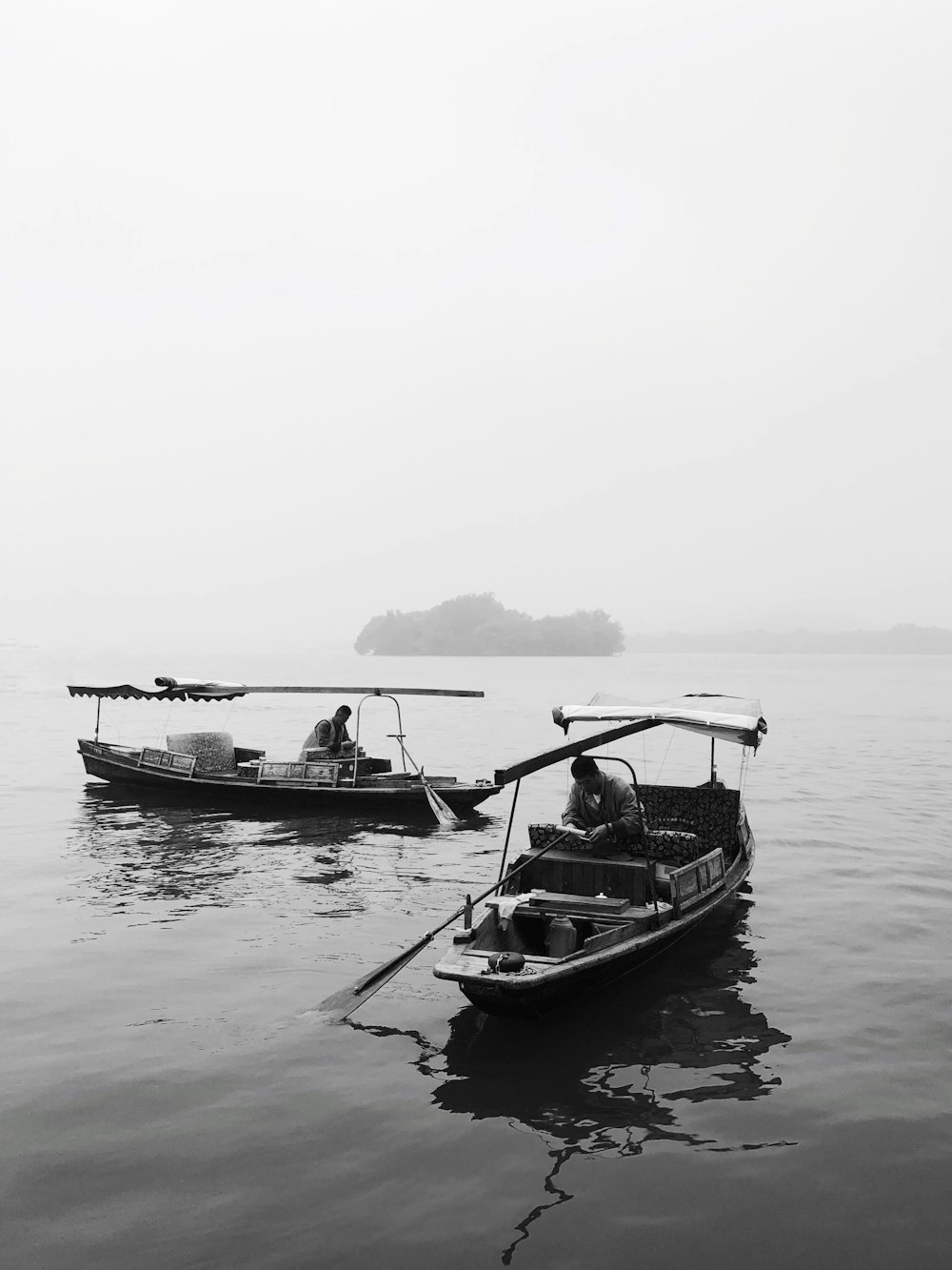grayscale photography of two boats near island