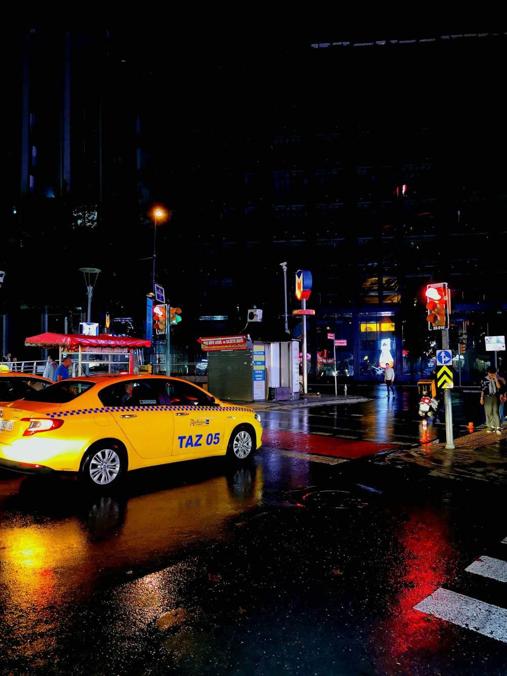 Táxi amarelo passando pela estrada molhada durante a noite