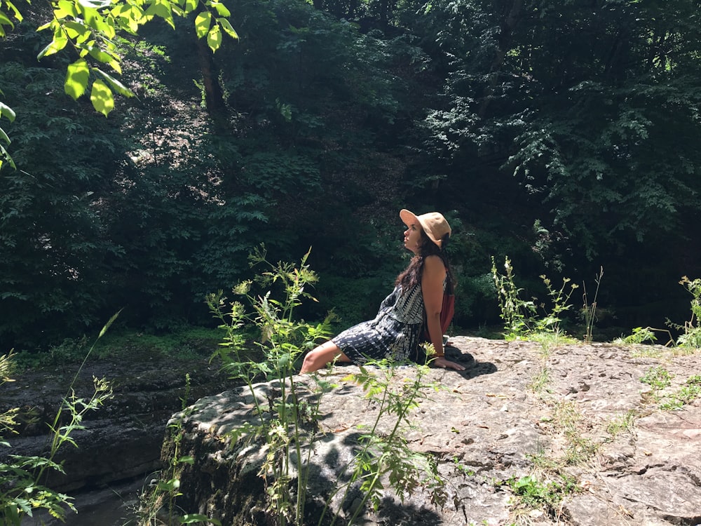 Mujer sentada en la roca en el bosque