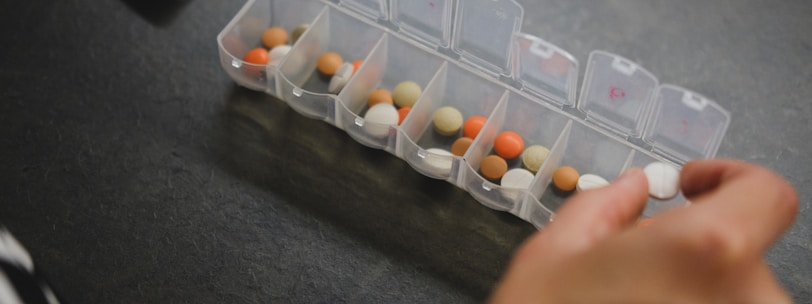 person about to pick medicine from medicine organizer