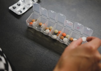 person about to pick medicine from medicine organizer