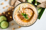 A colorful bowl of hummus garnished with olive oil and parsley.