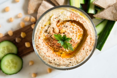 A colorful bowl of hummus garnished with olive oil and parsley.