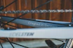 Close-up of a handcrafted bicycle frame with the radkunst logo in a cozy workshop setting