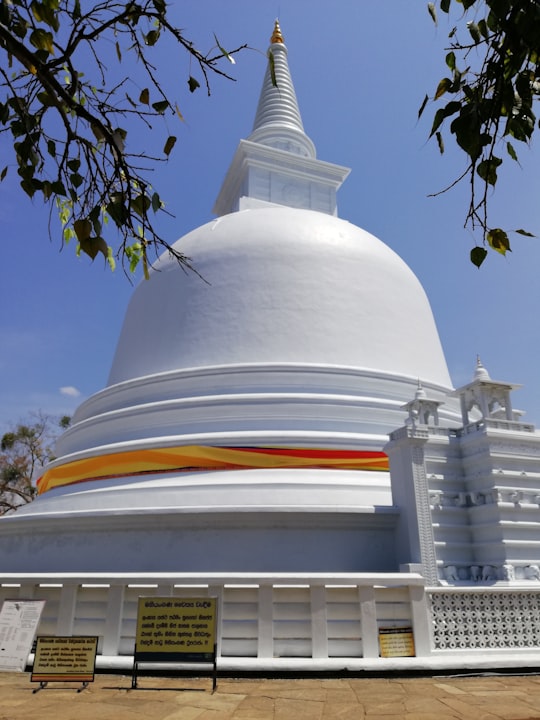 bell-shaped white building structure under blue sky in Mahiyangana Raja Maha Vihara Sri Lanka