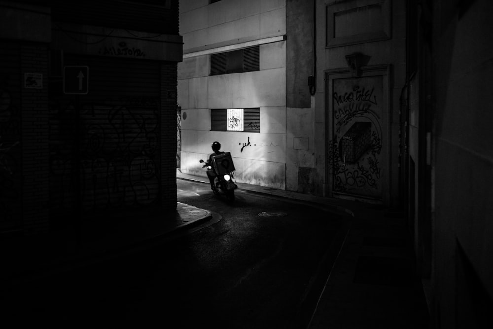 grayscale photo of a delivery motorcycle in an alley