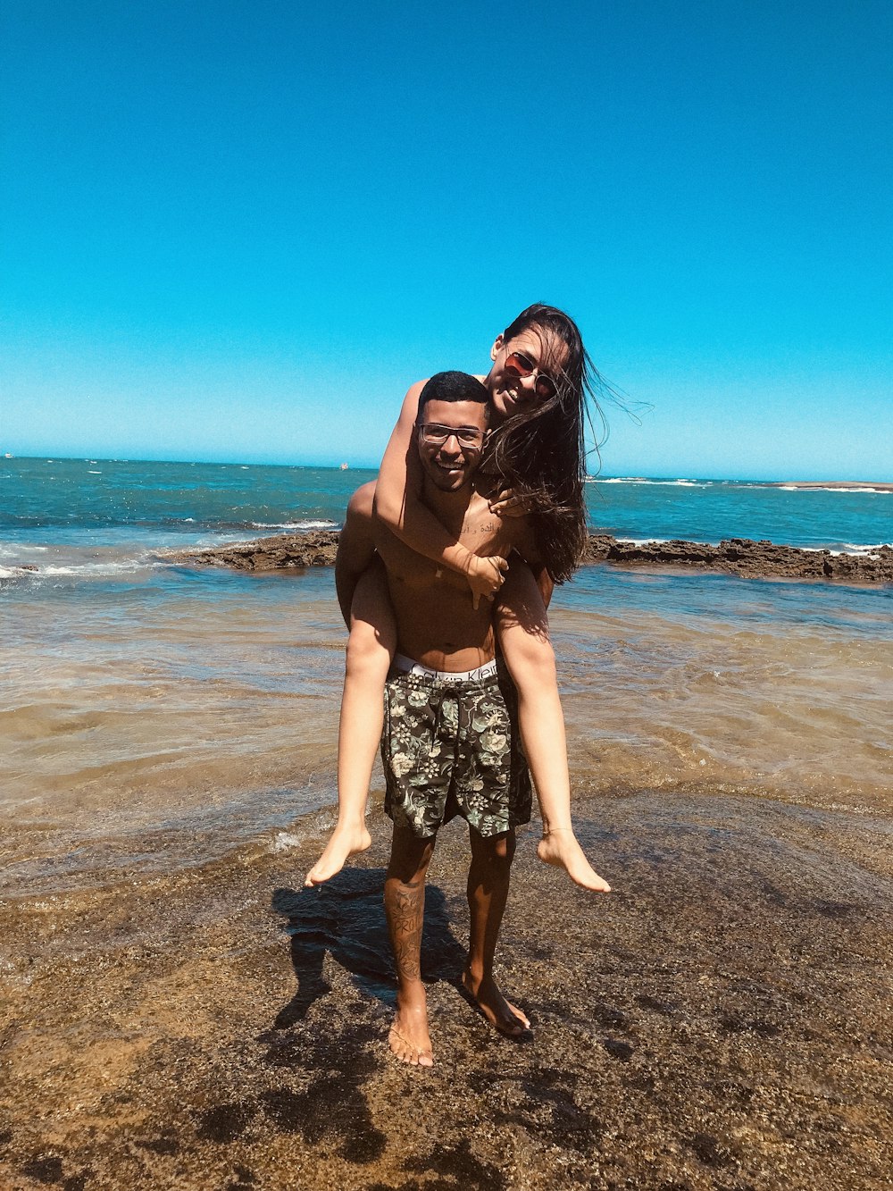 man carrying woman standing near beach