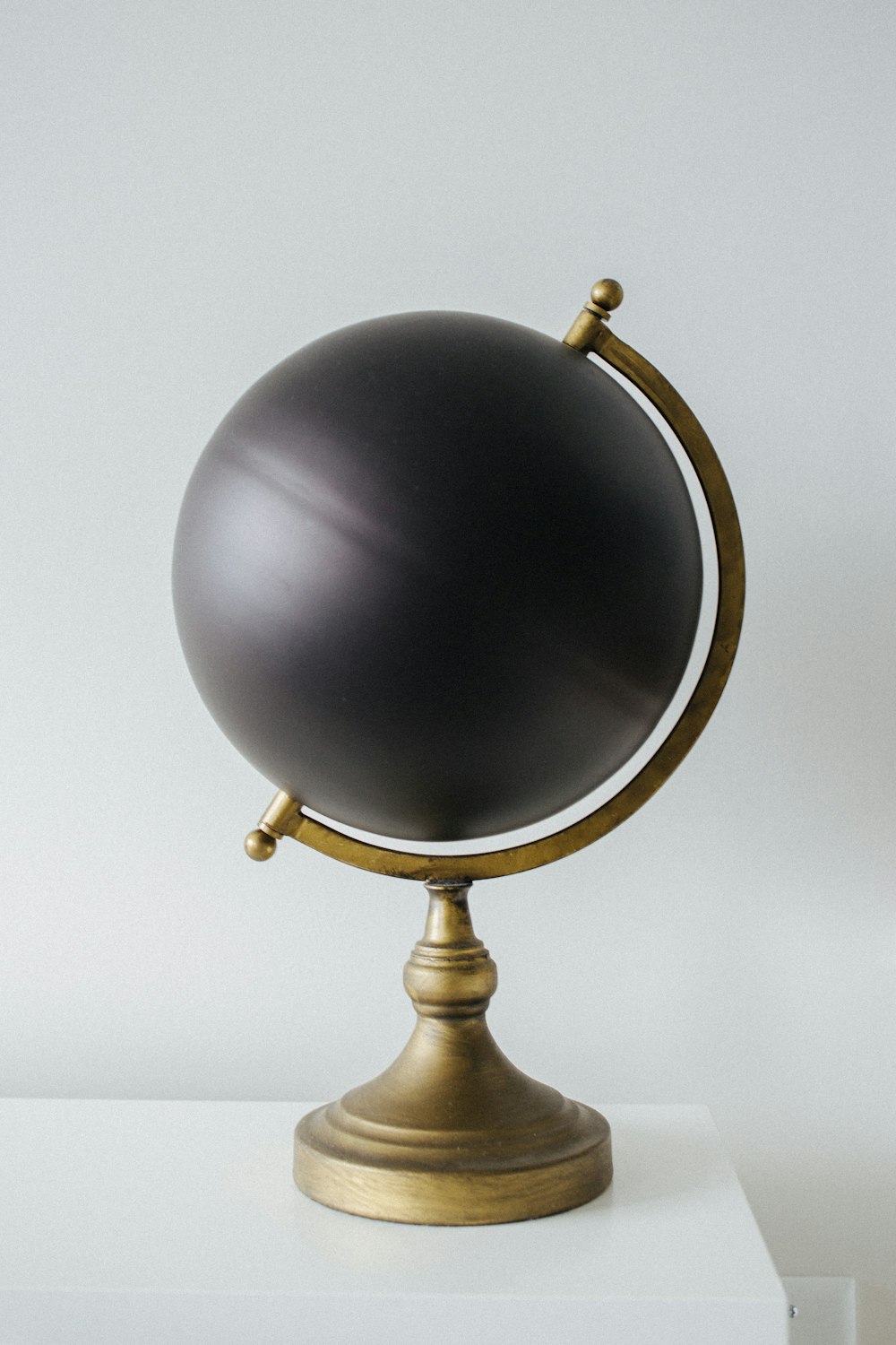 un globe noir posé sur une table blanche