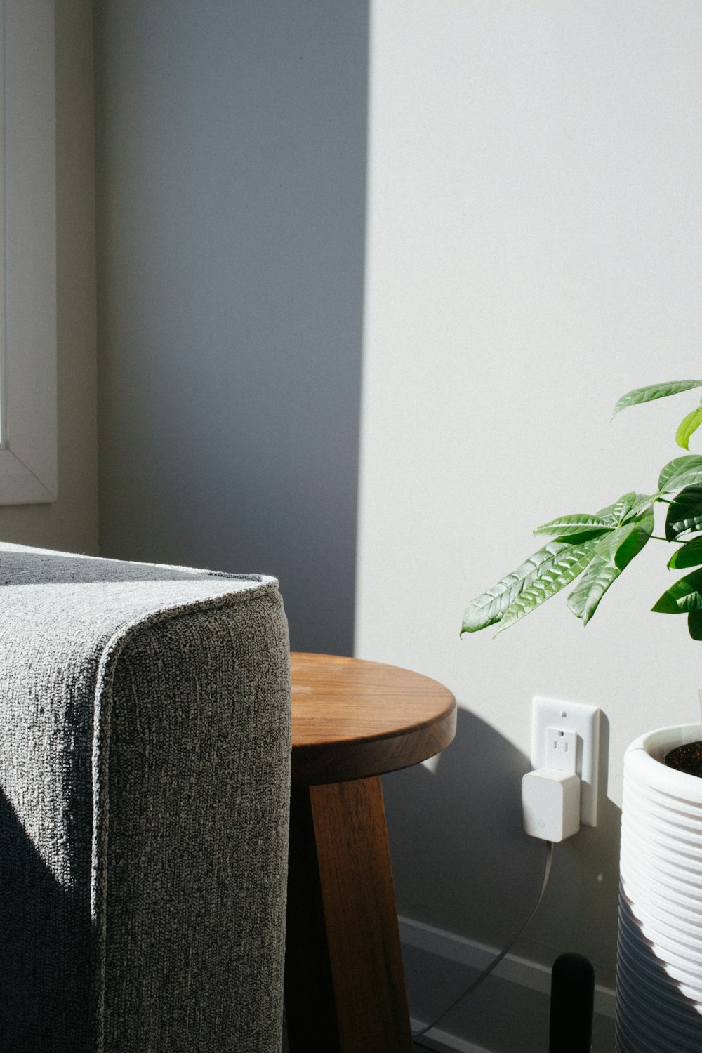 round wooden end table near wall socket