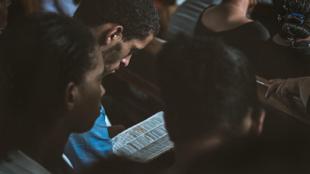 man reading a book beside people